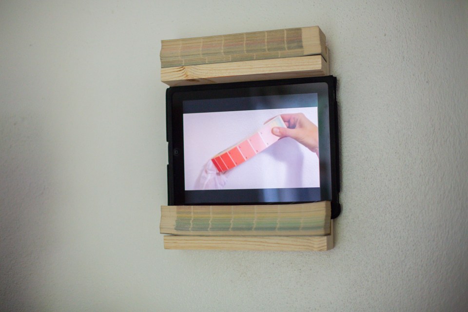 [Installation shot from Lily Kuonen's "Dreaming in Color,"  2013, Benjamin Moore paint swatches, single-channel video loop, iPad, 12” H by 3” W by 10” L.]